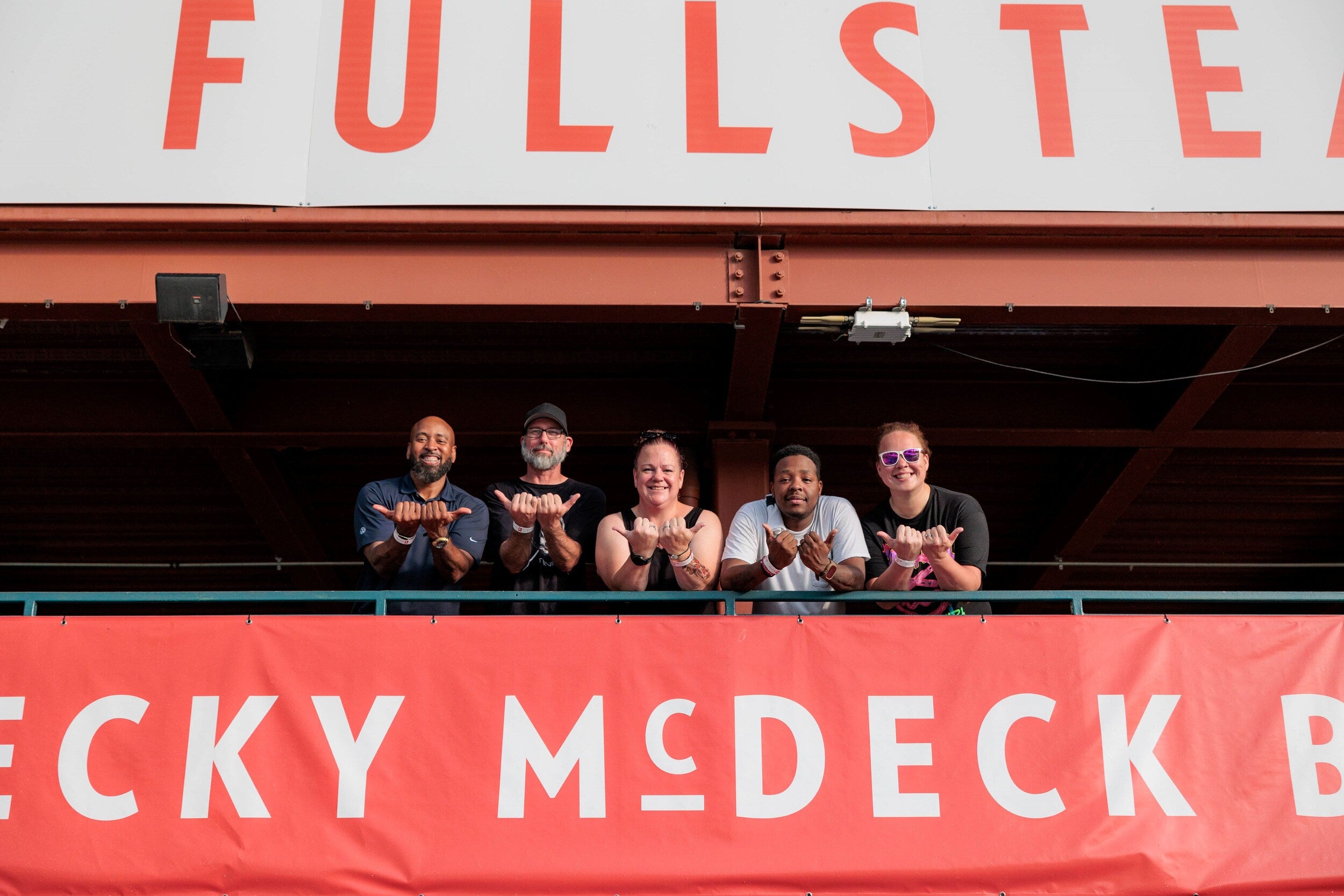 Group of people standing on a balcony holding food at an event.