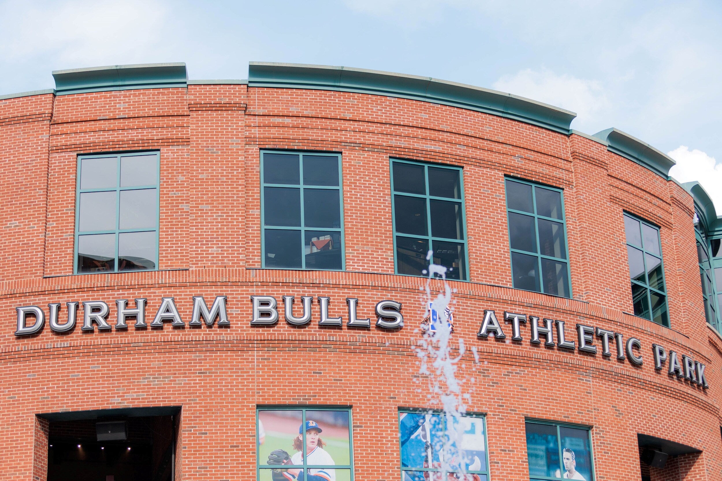 Exterior view of Durham Bulls Athletic Park with its red brick facade and large signage.